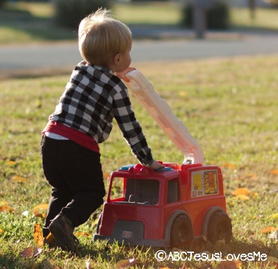 Preschool boy playing outside with firetruck.