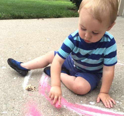 Toddler playing with chalk.