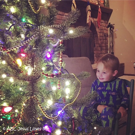 Little boy looking at a Christmas tree.