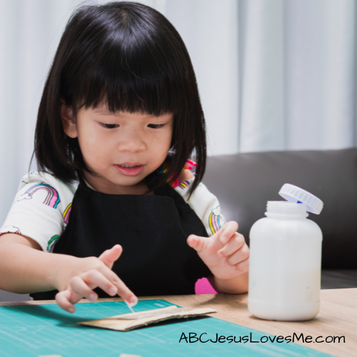 Child gluing on construction paper.