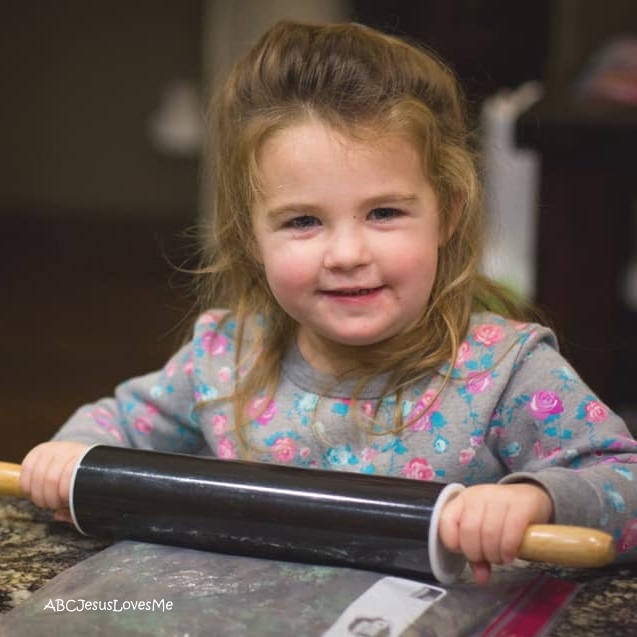 A little girl with a roller pin.