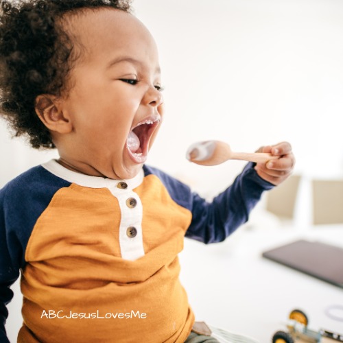 Toddler using a spoon to eat.