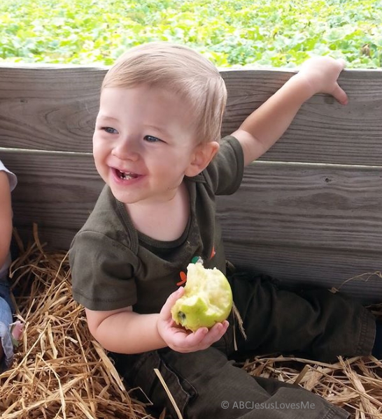 Child sitting in wagon with apple