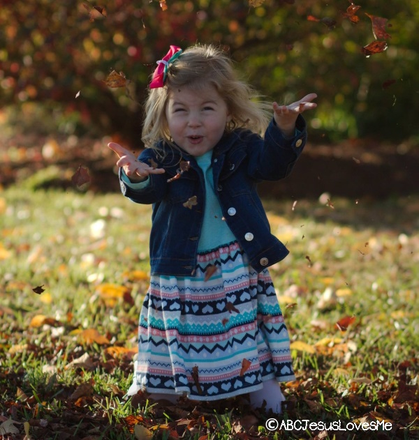 Little girl playing in the leaves.