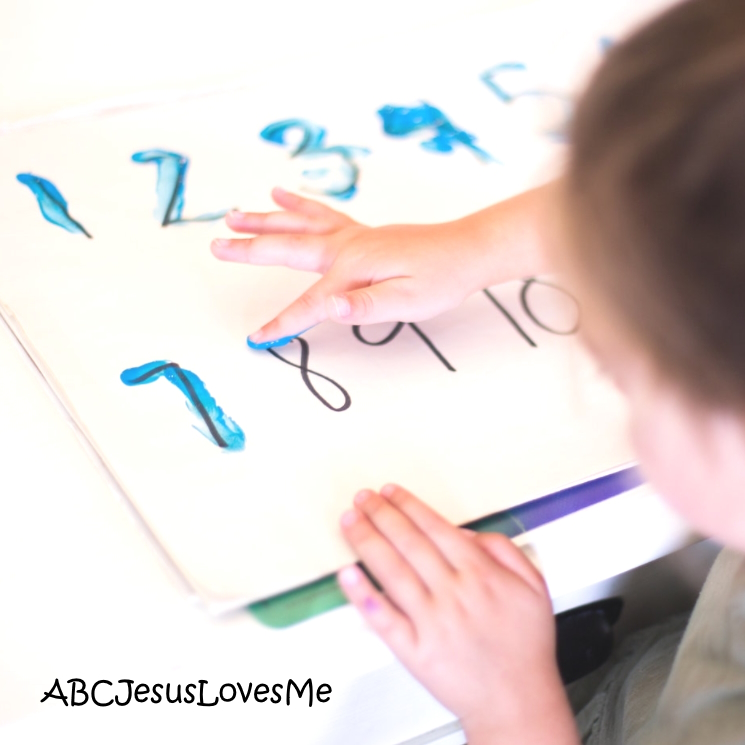 A child tracing numbers with fingerpaint.