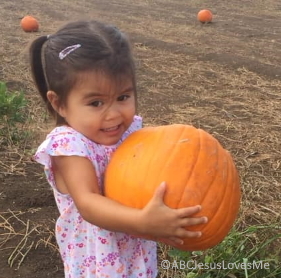 Little girl holding a large pumpkin