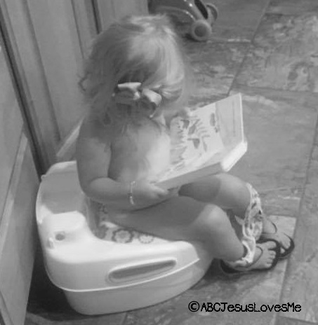 Little girl reading while on the potty.