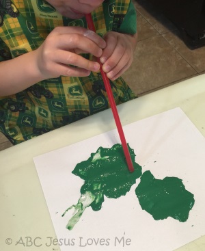 Child painting by blowing into a straw.