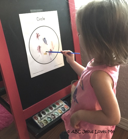 Preschool girl painting on an easel.