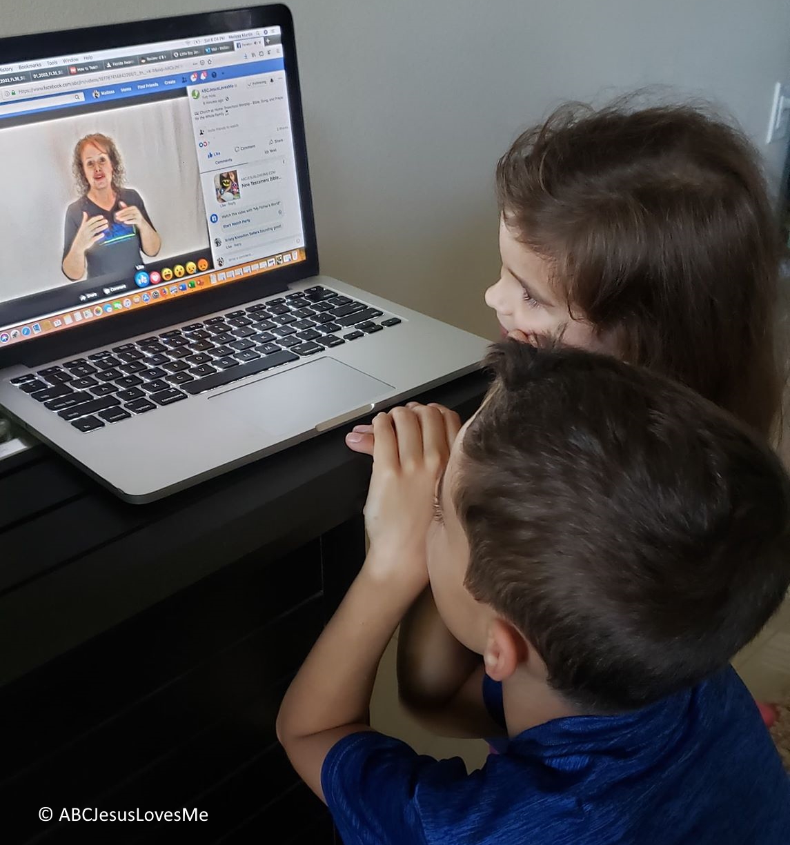Two children watching Ms Heidi on a laptop